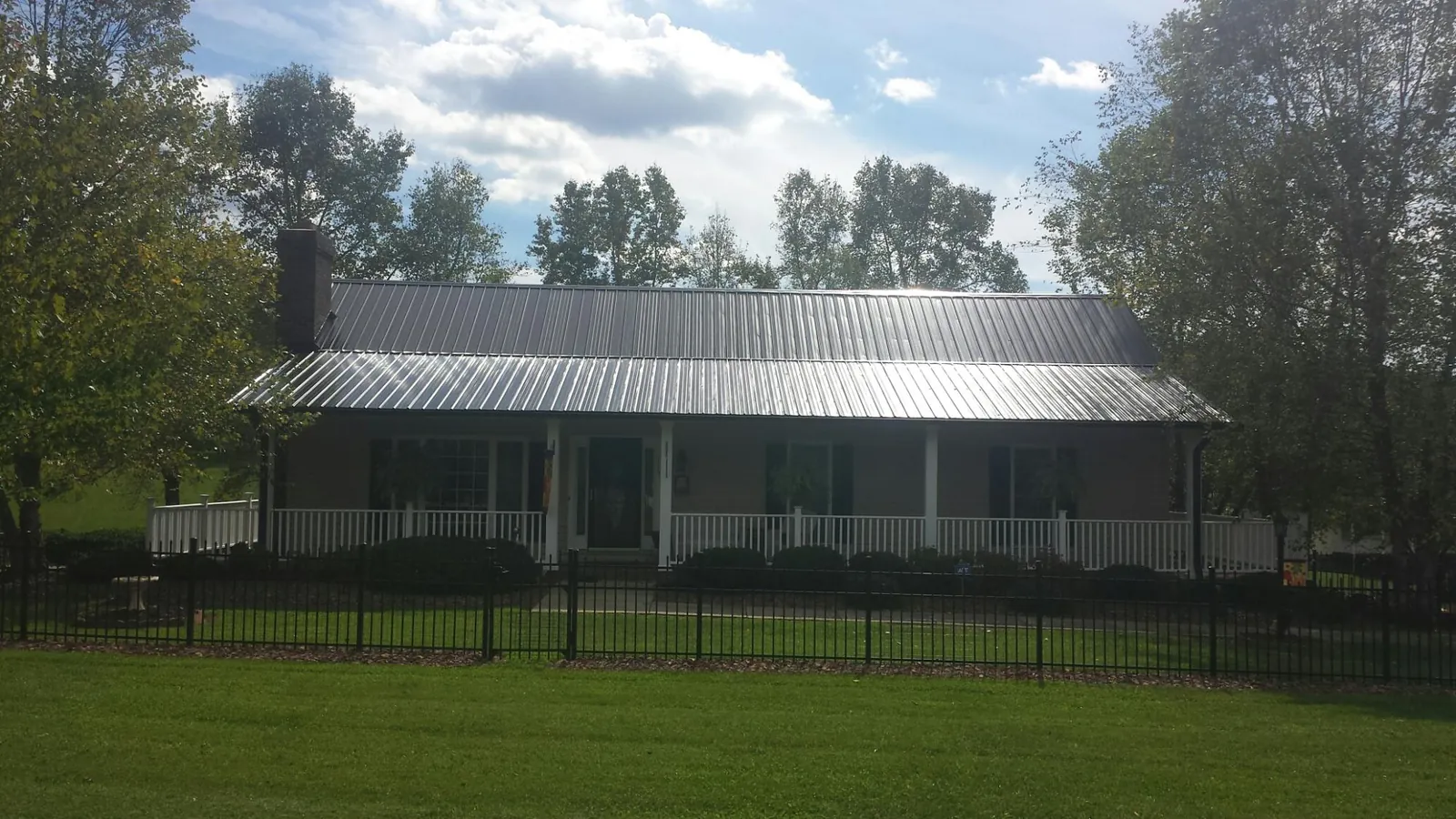 Gray metal roof on a brick ranch with a full width front porch — Gutter Guard Installation work by our crew in Patterson